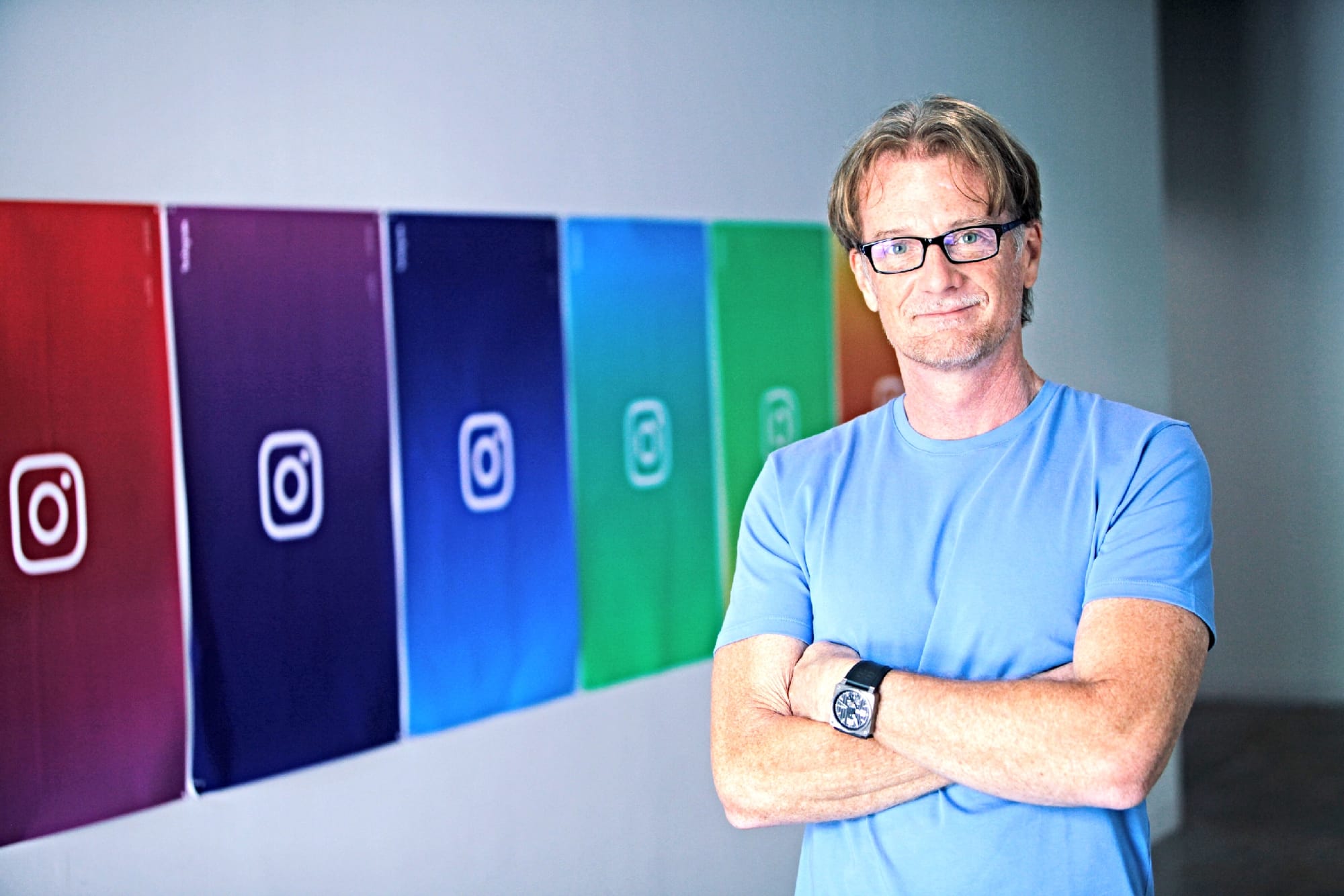 James Everingham standing beside a row of colorful Instagram logo panels