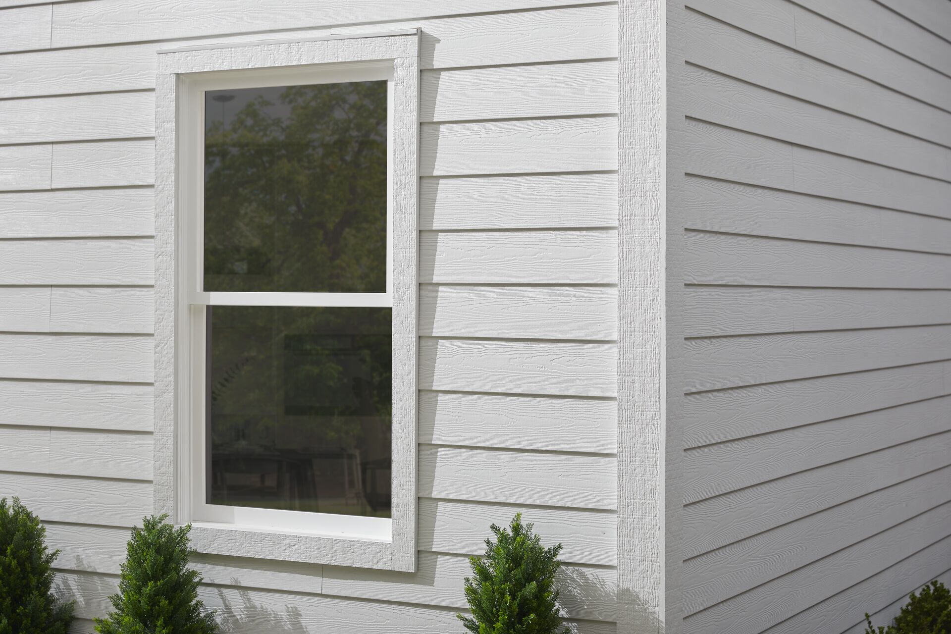 White woodgrain lap siding with wide corner and window trim on a finished home