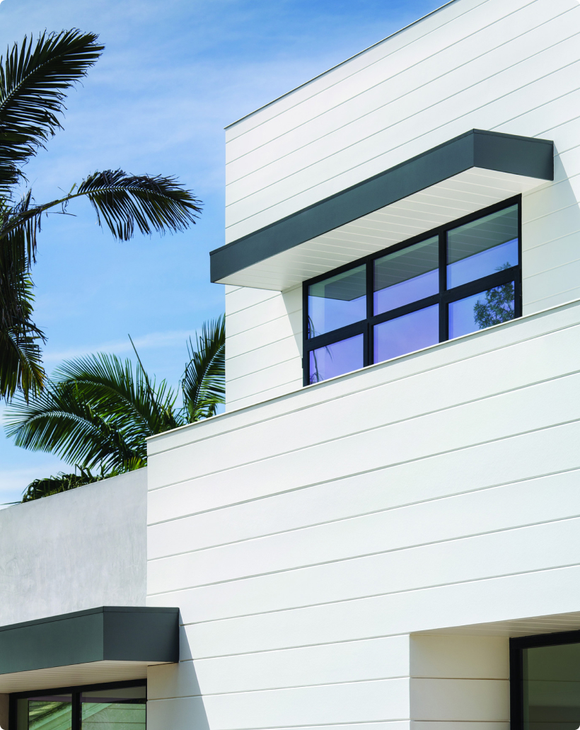 White Hardie Artisan V-Groove siding on a modern home, framed by palms and dark window trim