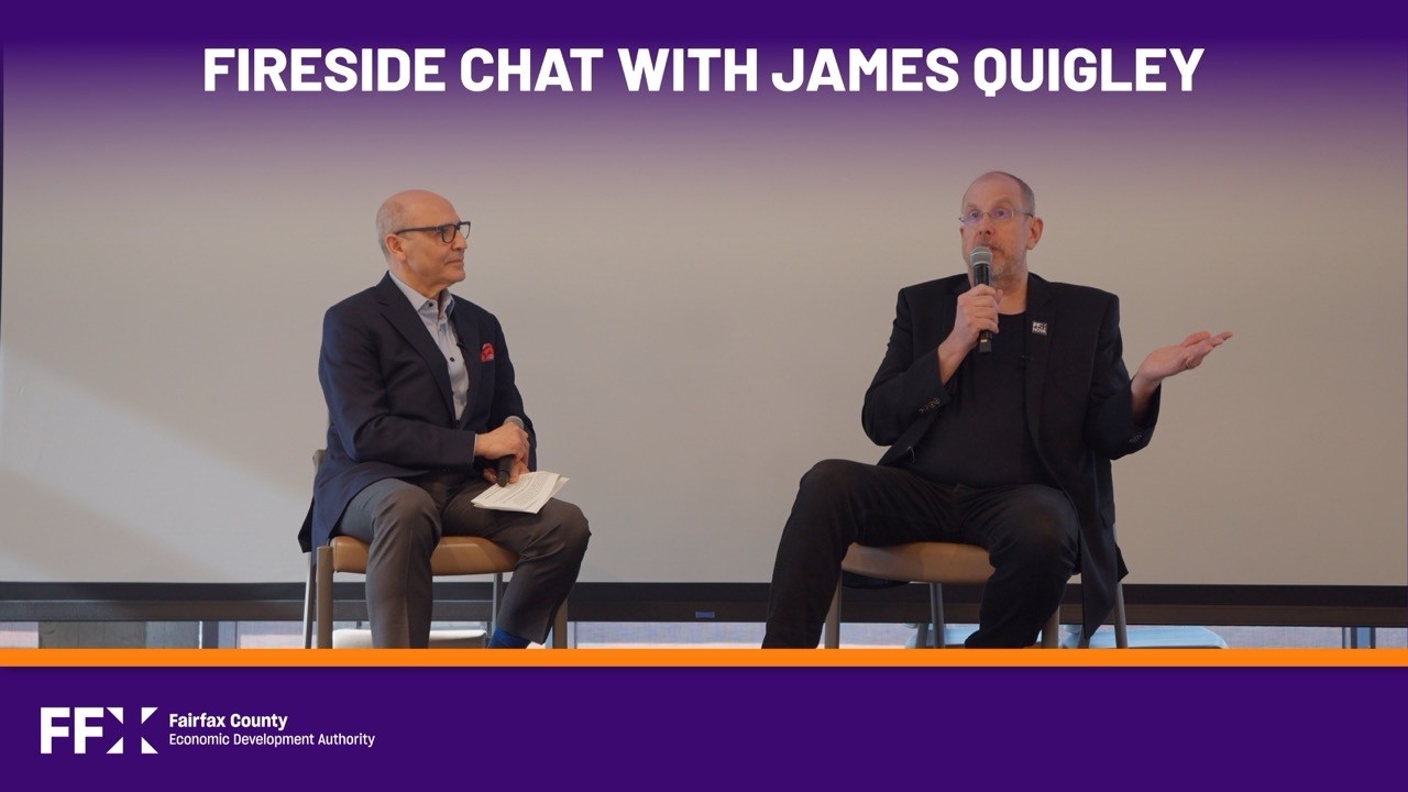 Victor Hoskins, left, in conversation with James Quigley, who holds a microphone and gestures from his chair
