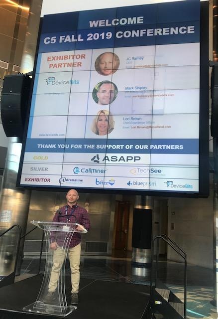 JC Ramey speaking at a transparent lectern beneath the C5 Fall 2019 conference display