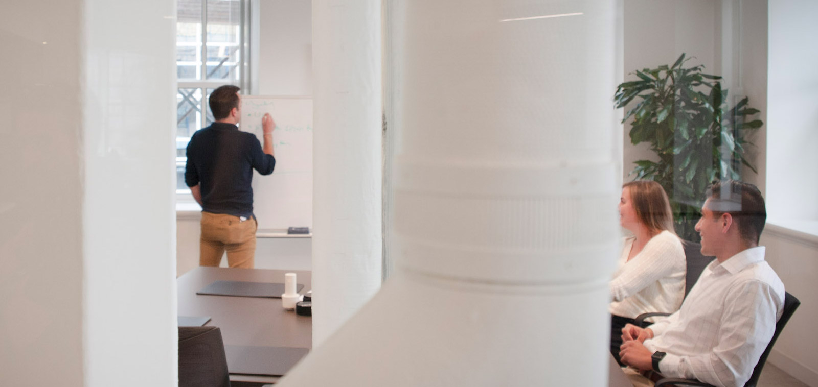 James Ward seated at right with a colleague while another colleague writes on a whiteboard