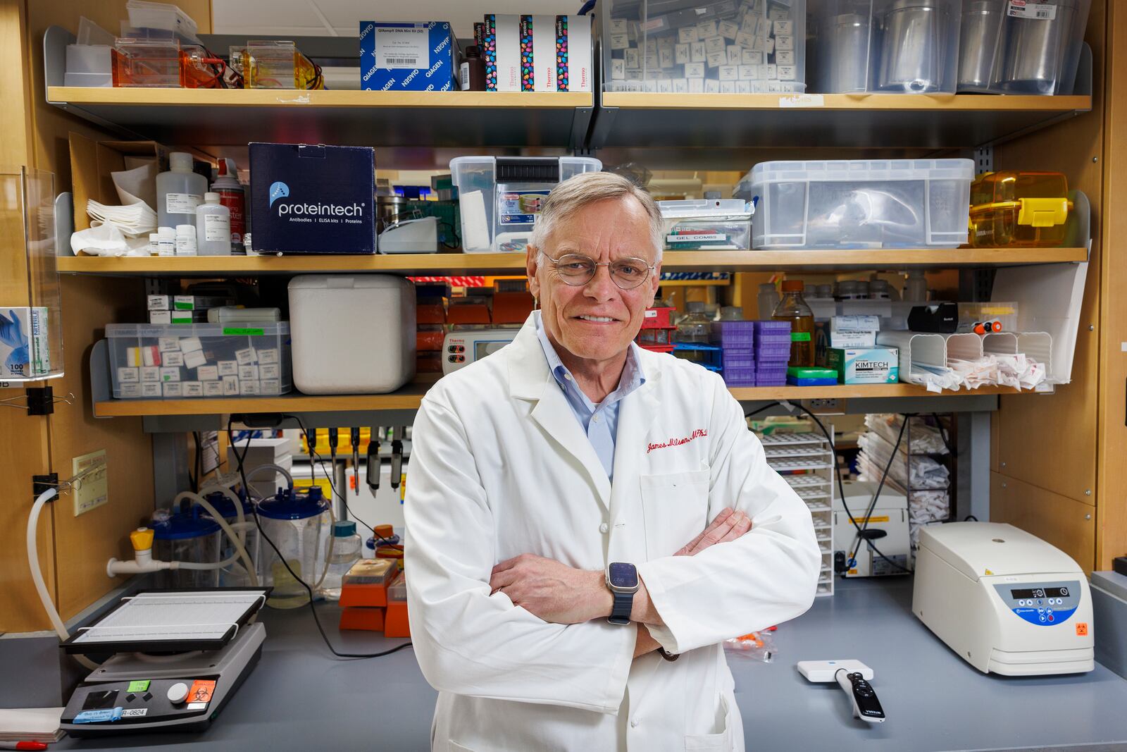 James M. Wilson standing in GEMMABio’s Philadelphia laboratory, in front of shelves of research equipment