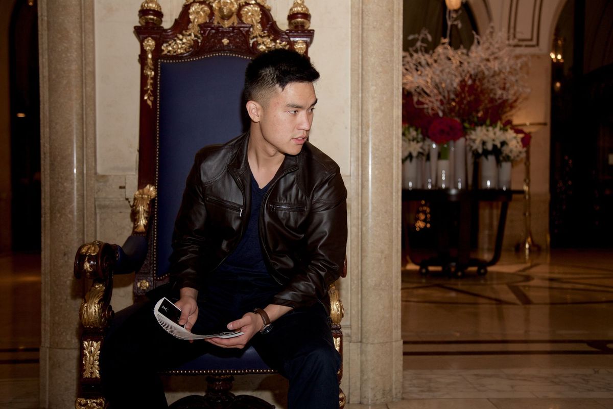 Jamie Chen seated in an ornate chair while holding a spread deck of cards