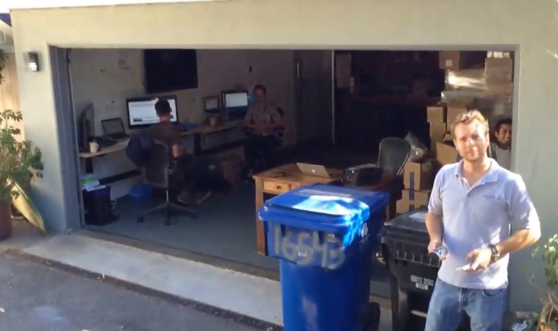 Jamie Siminoff outside the open garage where the early Ring team worked, with desks and boxes behind him