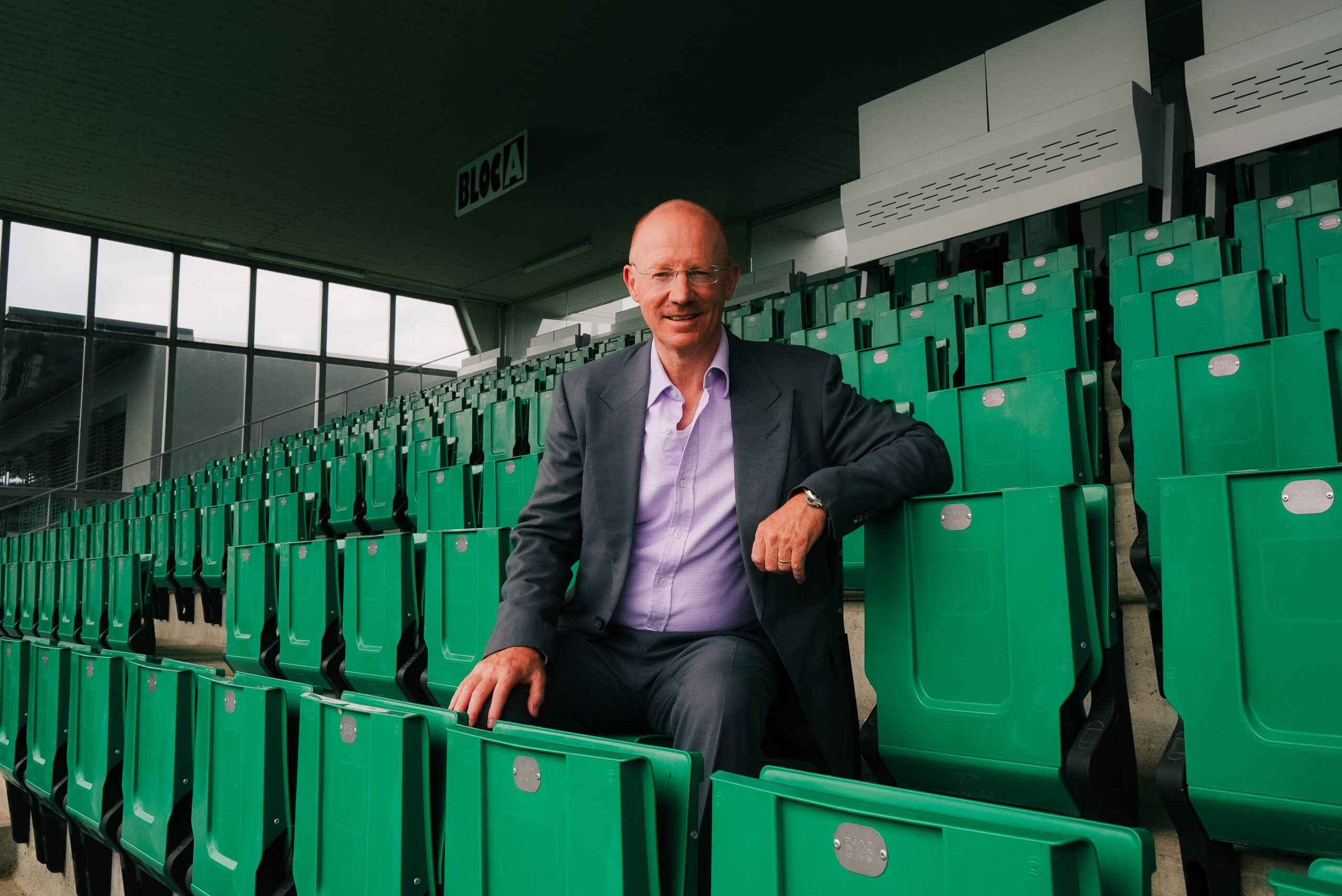 Jamie Welch sitting among green seats at Yverdon Sport's stadium