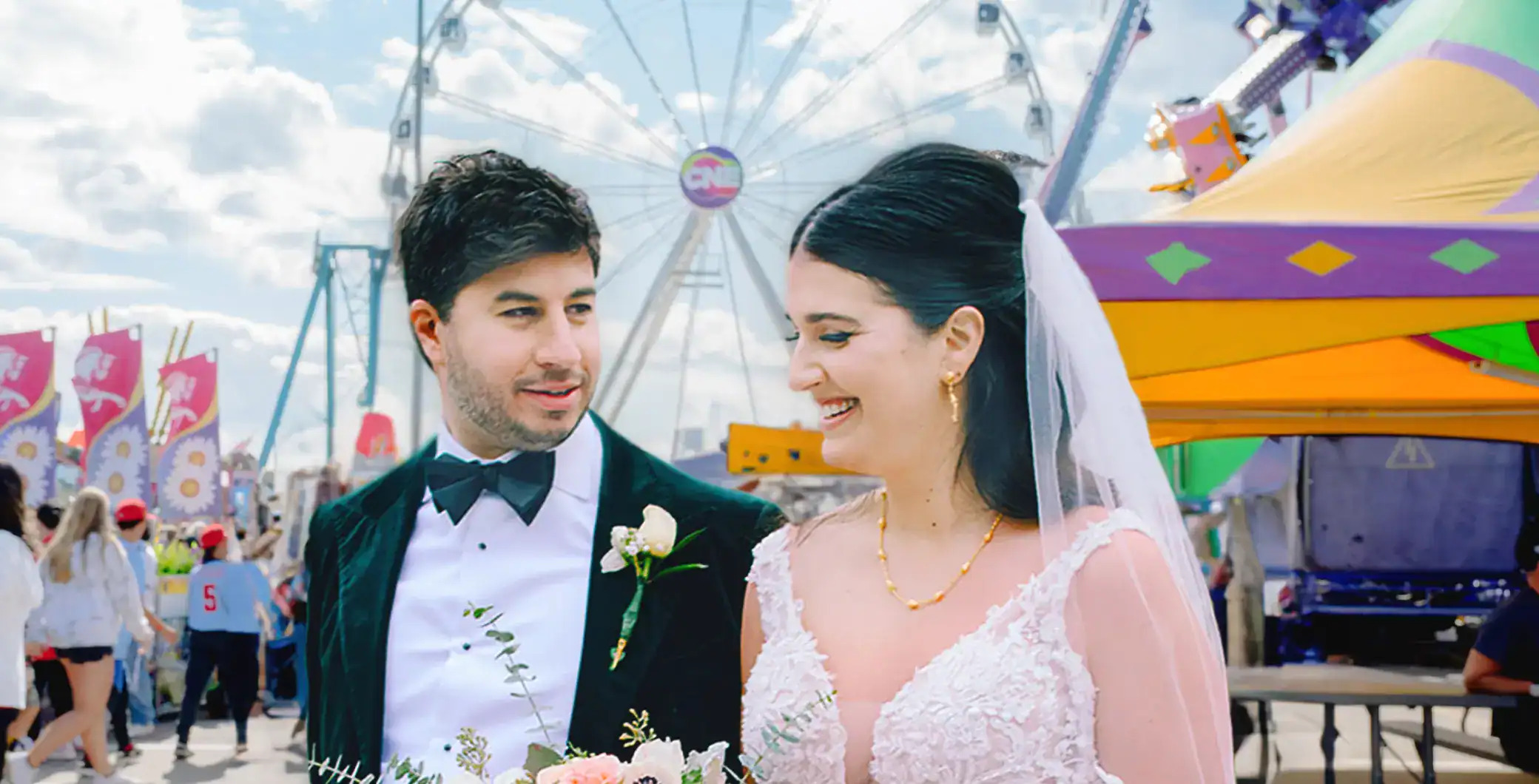 A couple celebrating beneath the lights of the CNE midway, with the SuperWheel behind them