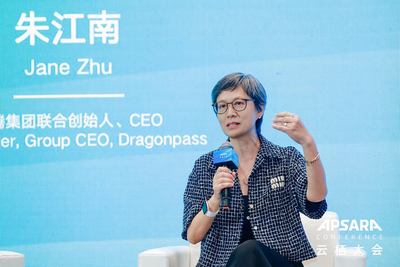 Jane Zhu holding a microphone while speaking at the Apsara Conference, with her name displayed behind her