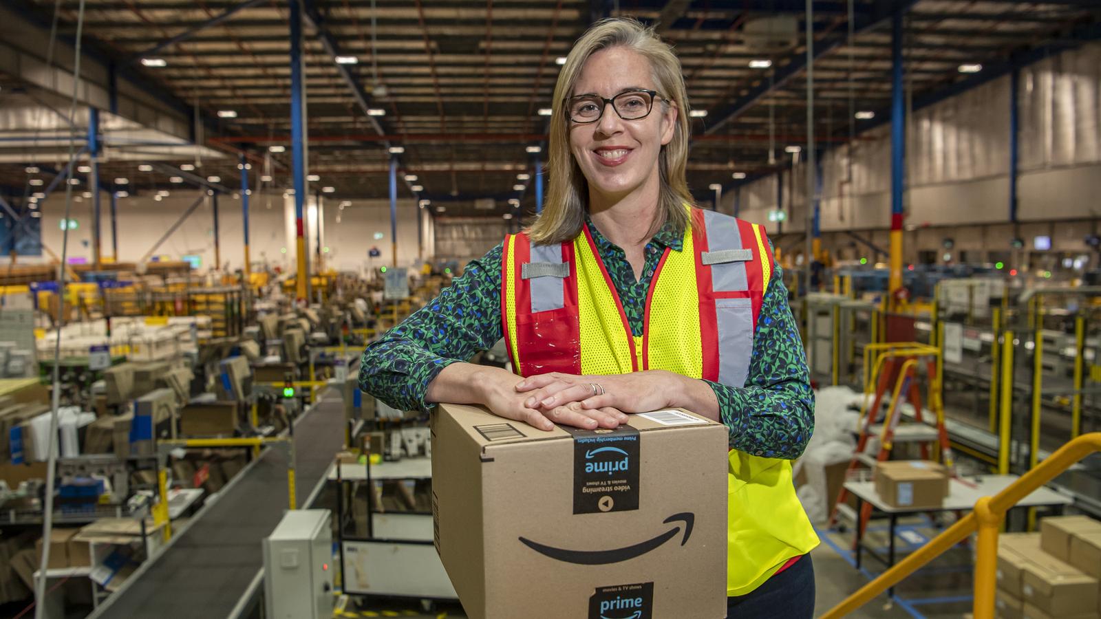 Janet Menzies wearing a high-visibility vest at Amazon’s Moorebank fulfilment centre, with a parcel in front of her