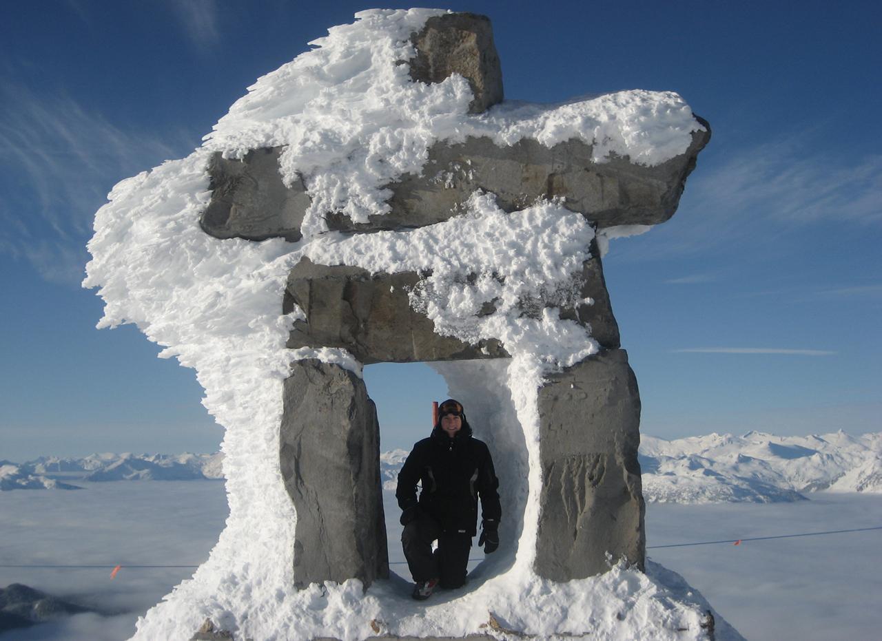 Jared Golden standing beneath a large snow-covered stone structure against a mountain backdrop