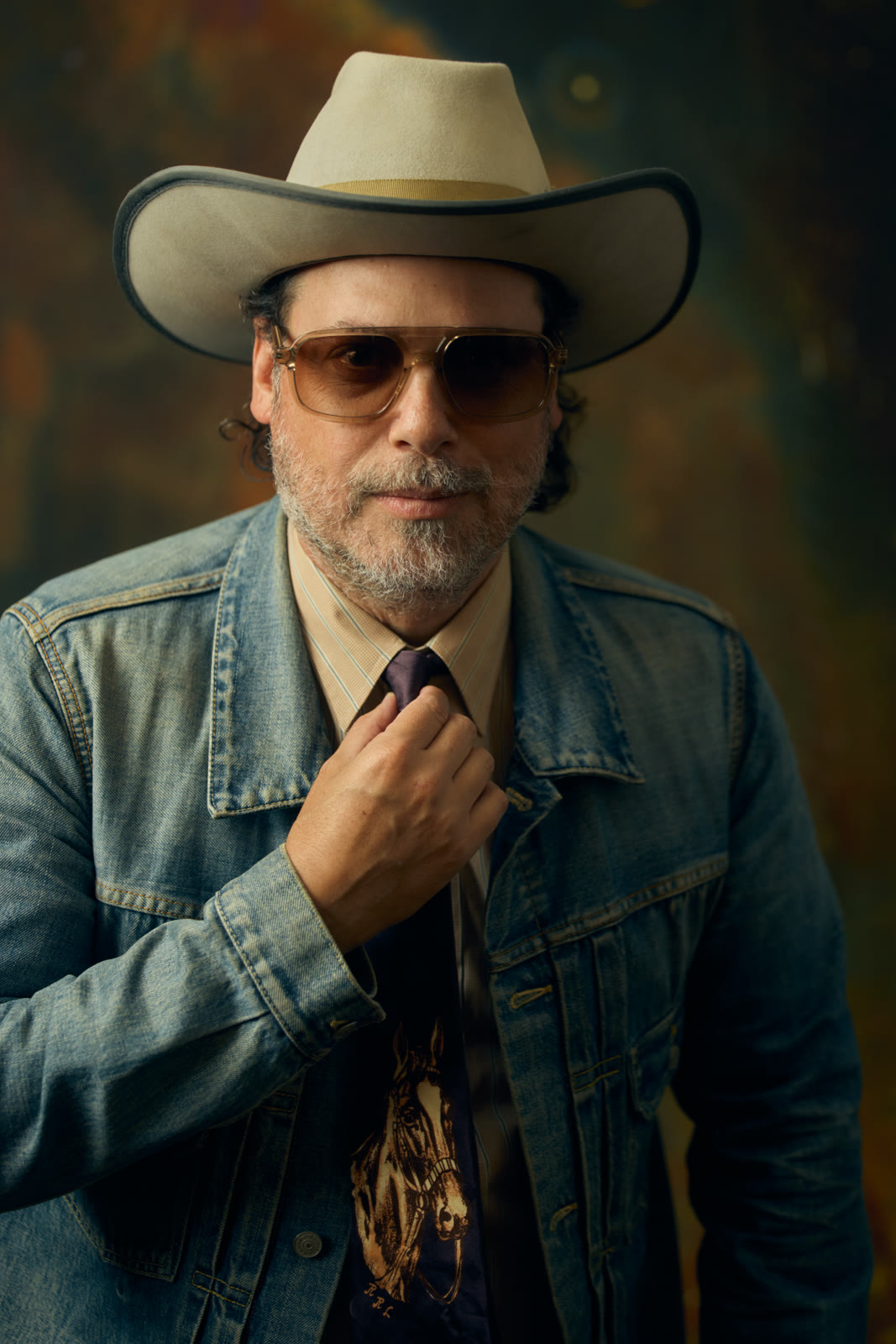 Jared Gutstadt wearing a cowboy hat, sunglasses and a denim jacket, adjusting his tie