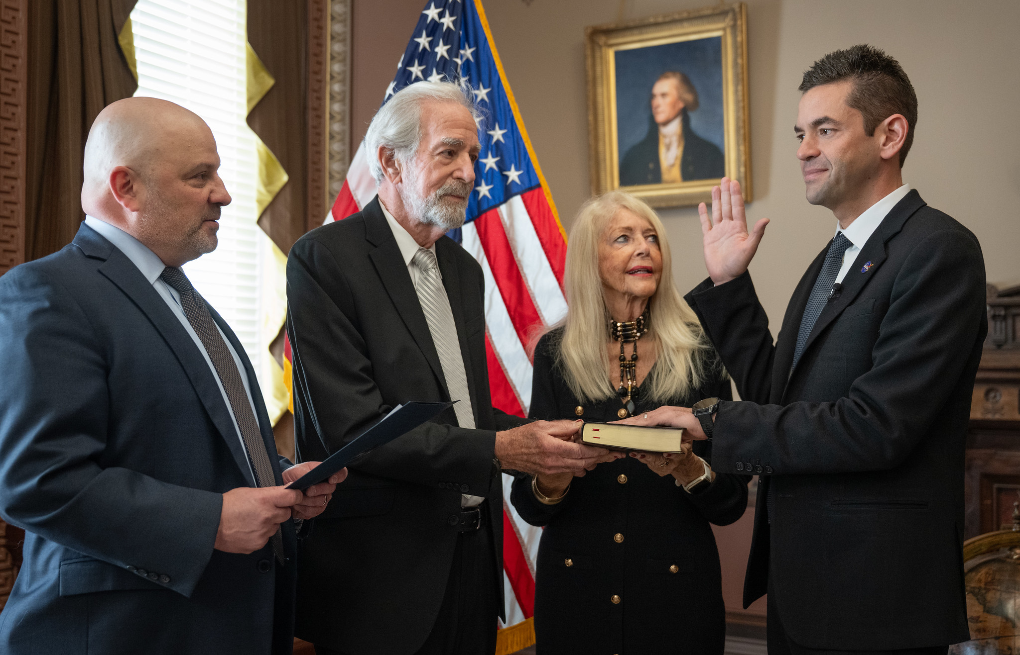 Jared Isaacman raises his right hand while taking the NASA administrator’s oath beside his parents and Judge Timothy Kelly.