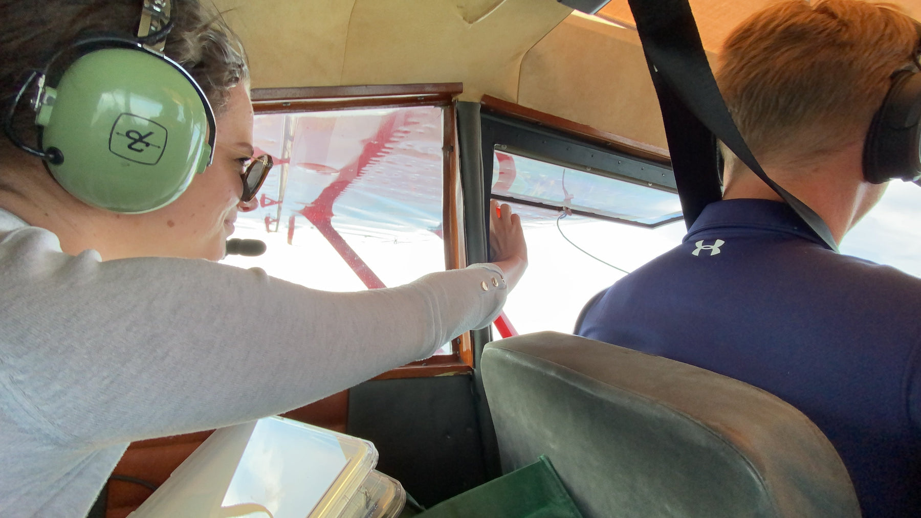 Inside the small plane, pilot Kenn flies while Jaide holds sampling equipment at the window.