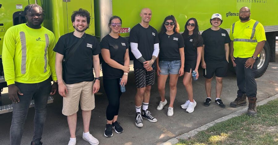 Members of the Village Media Cares team and GFL staff stand beside a green truck during a Toronto community gift distribution.