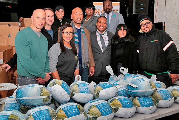 Jason Ackerman joins local officials and merchants behind a table of donated turkeys in the Bronx