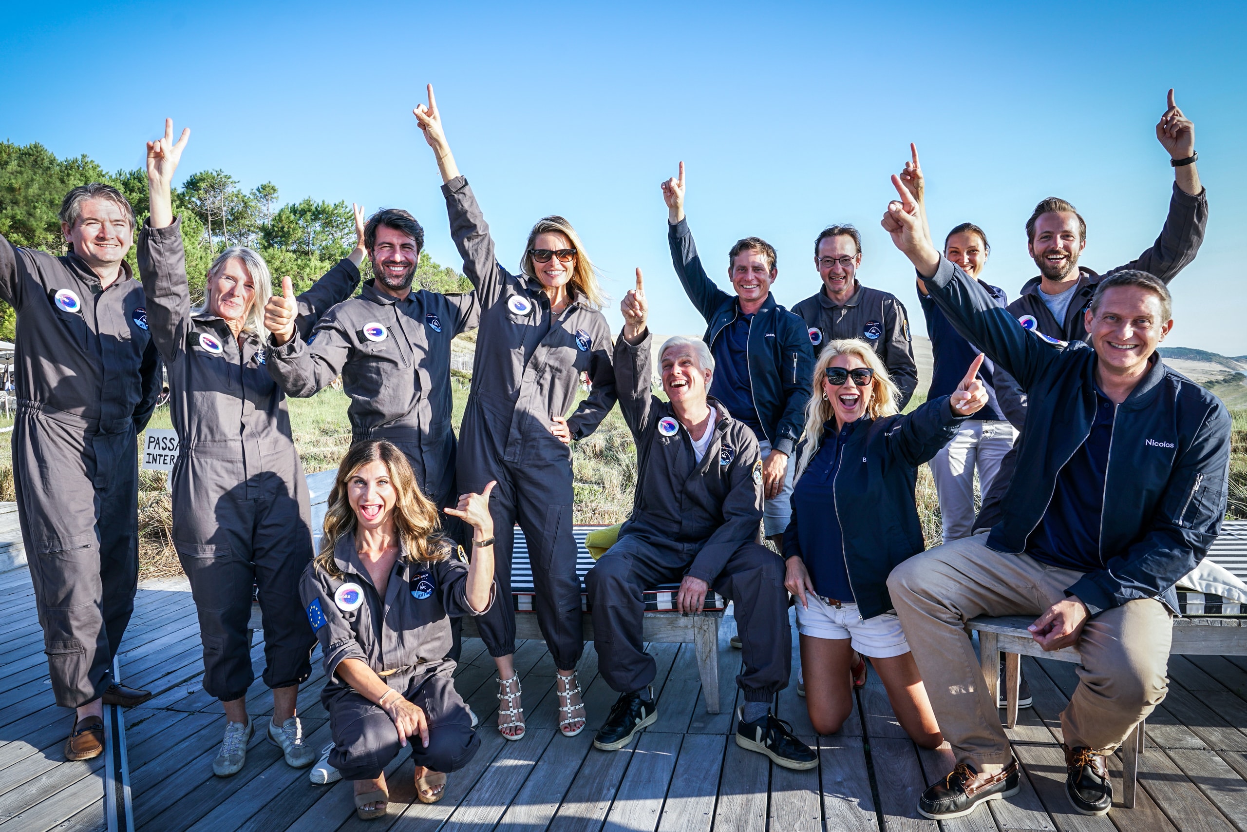 Jason Andrews and an Orbite graduation group outdoors, smiling and pointing toward the sky