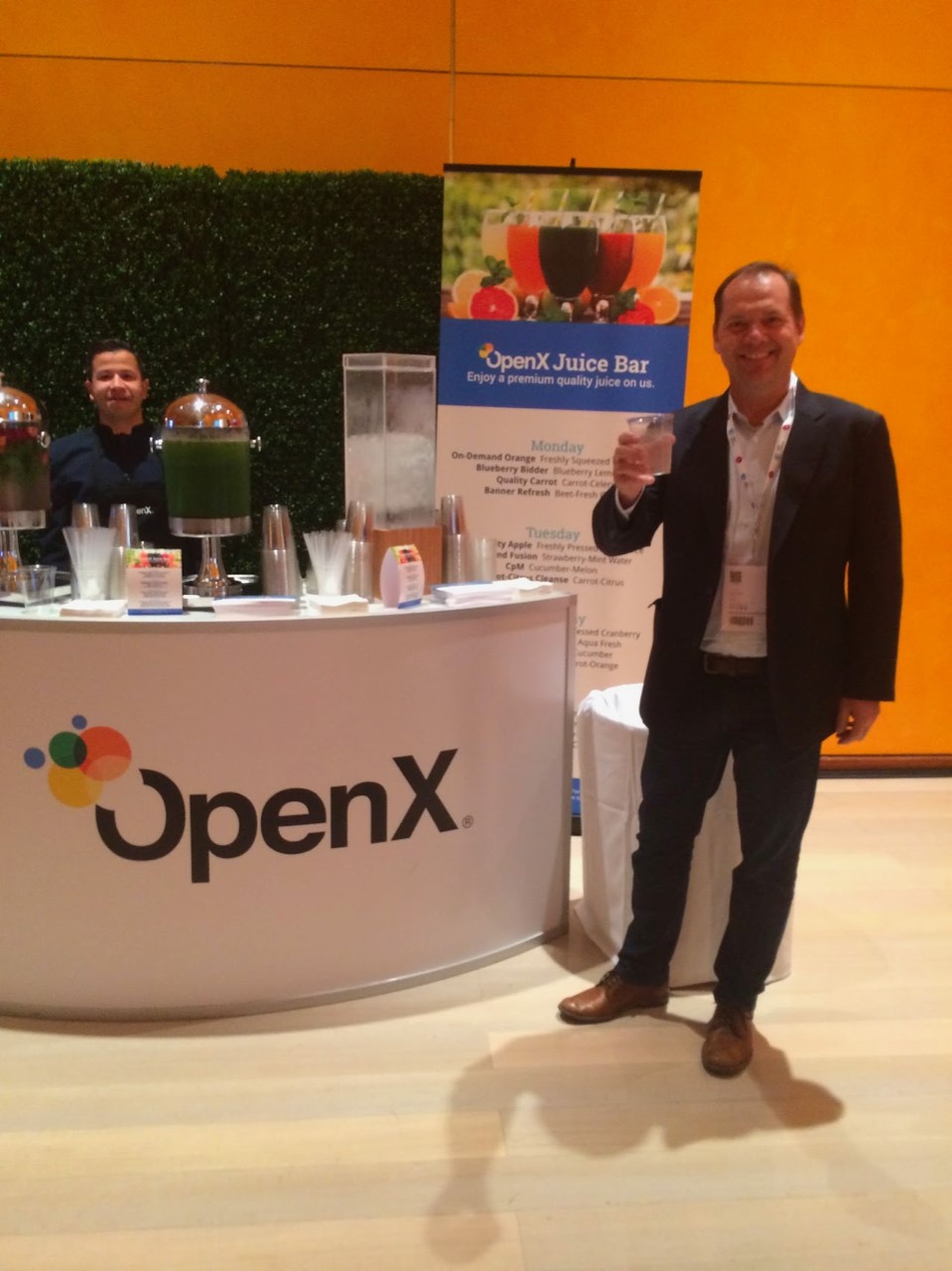 Jason Fairchild holding a drink beside an OpenX juice bar at an industry event