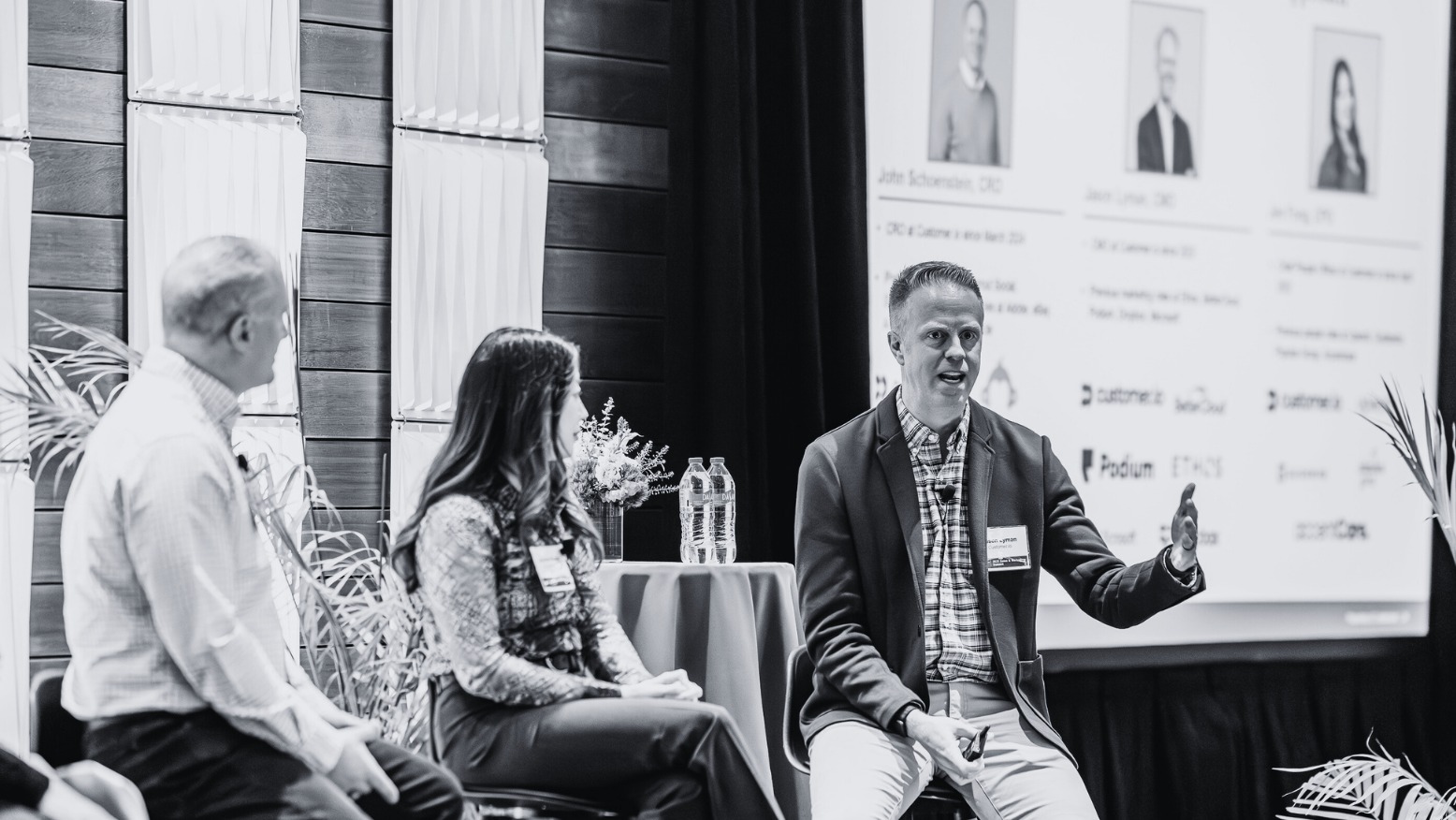 Jason Lyman speaking and gesturing during a seated business panel