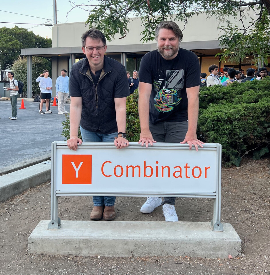Jason Okra, left, and Eric Rowell standing behind a Y Combinator sign