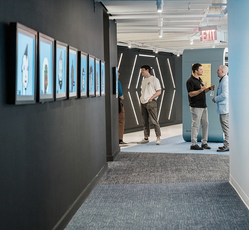 People standing beside a wall of framed artwork inside Galaxy’s New York office