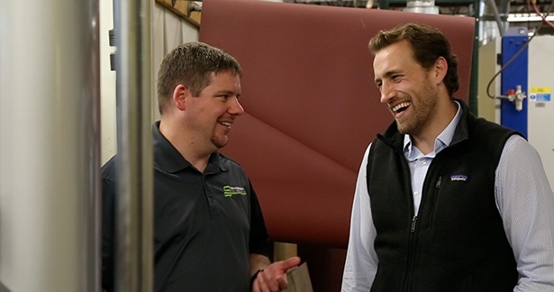 Jason Ray, right, talking with a customer inside a manufacturing shop