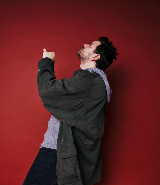 Jason Walker in a casual promotional portrait against a red background