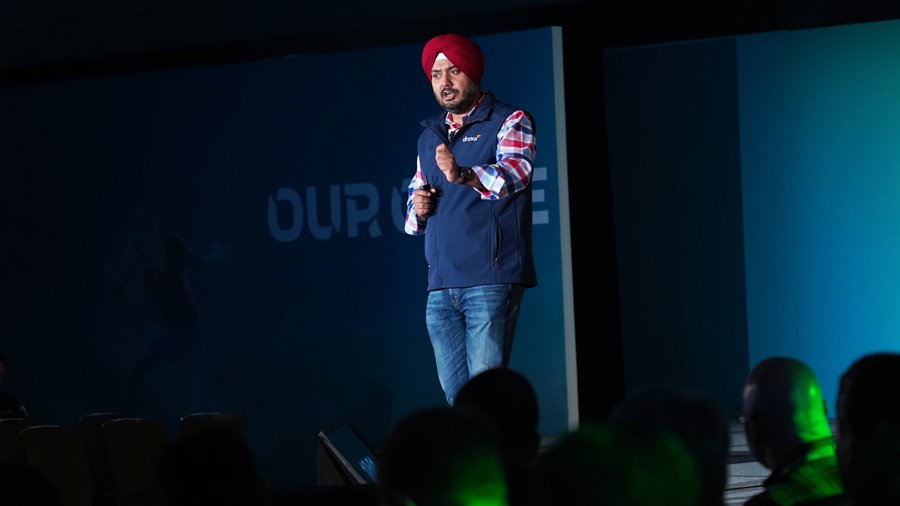 Jaspreet Singh speaking on a Druva stage, wearing a red turban and navy vest