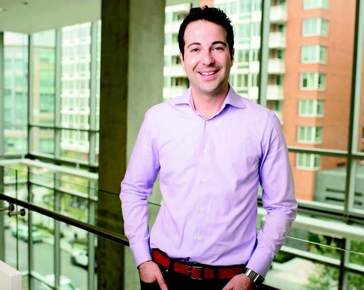 Jay Kaplan standing beside a glass railing in an office building
