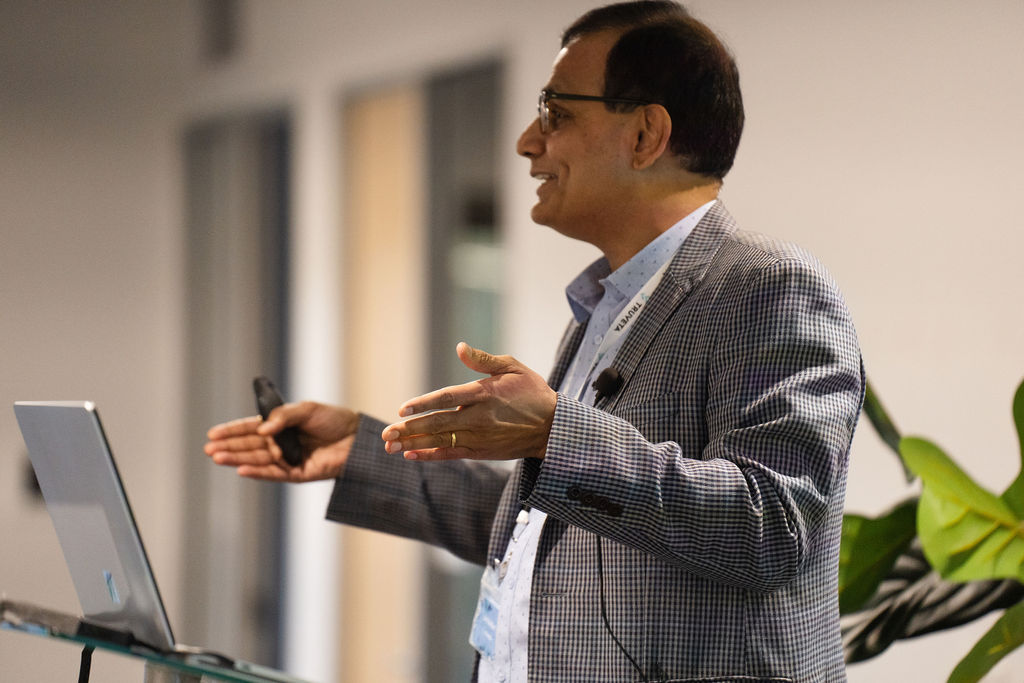 Jay Nanduri presenting beside a laptop at Truveta’s inaugural symposium in 2023