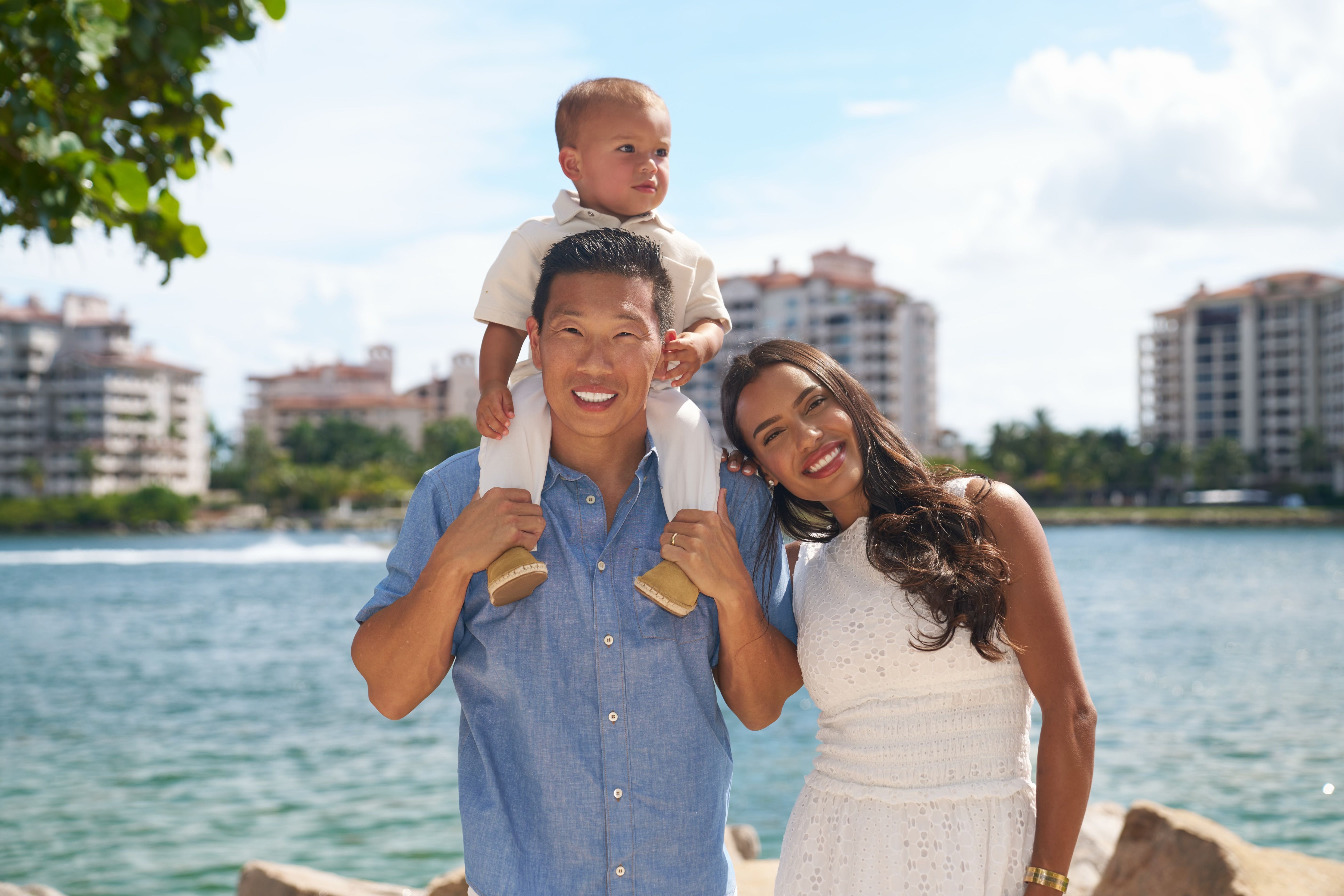 Jay Roberts outdoors with a woman and a child beside the water