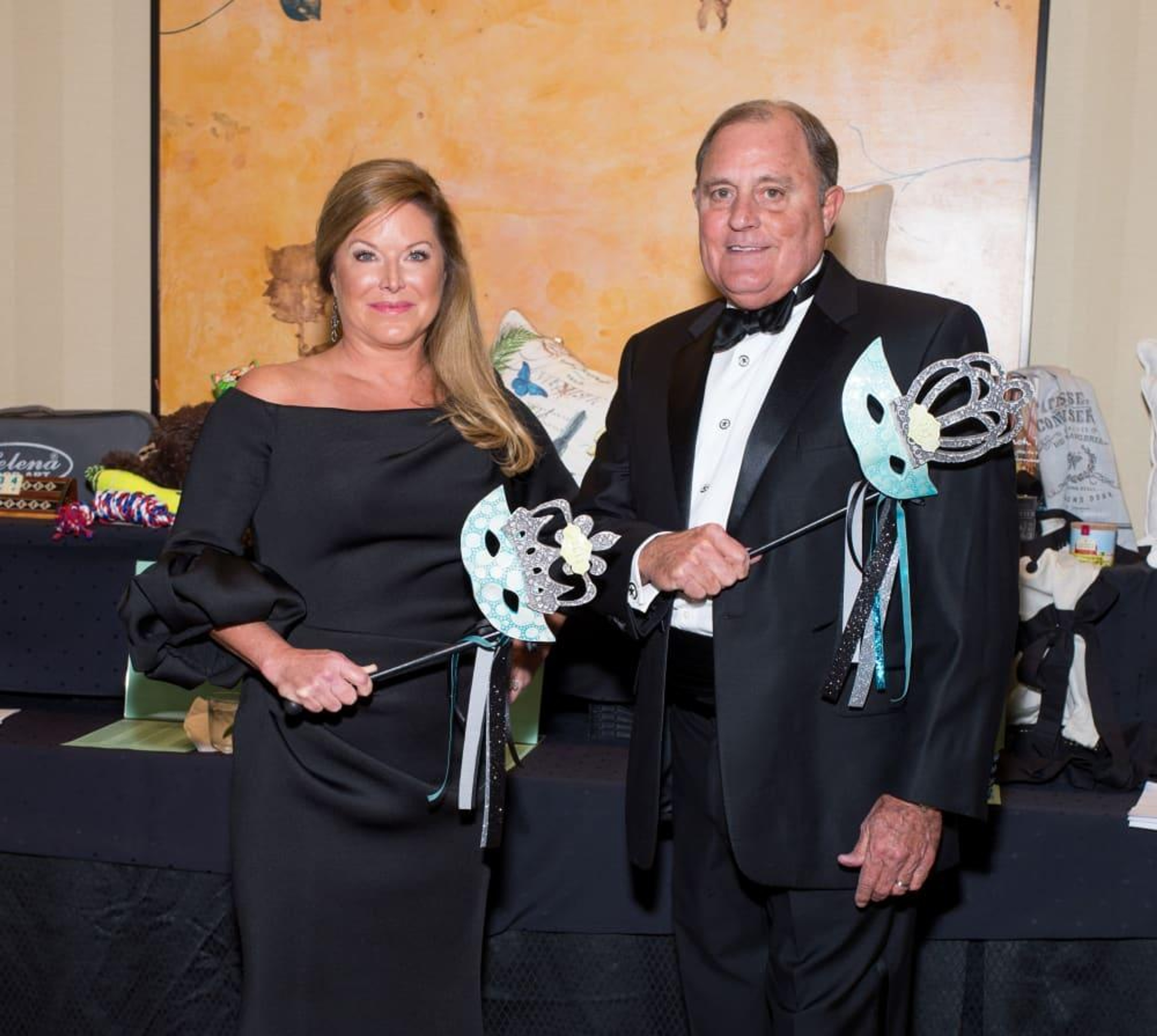 Julie and Jay Rogers holding decorative masks at the 2017 Covenant House Texas gala