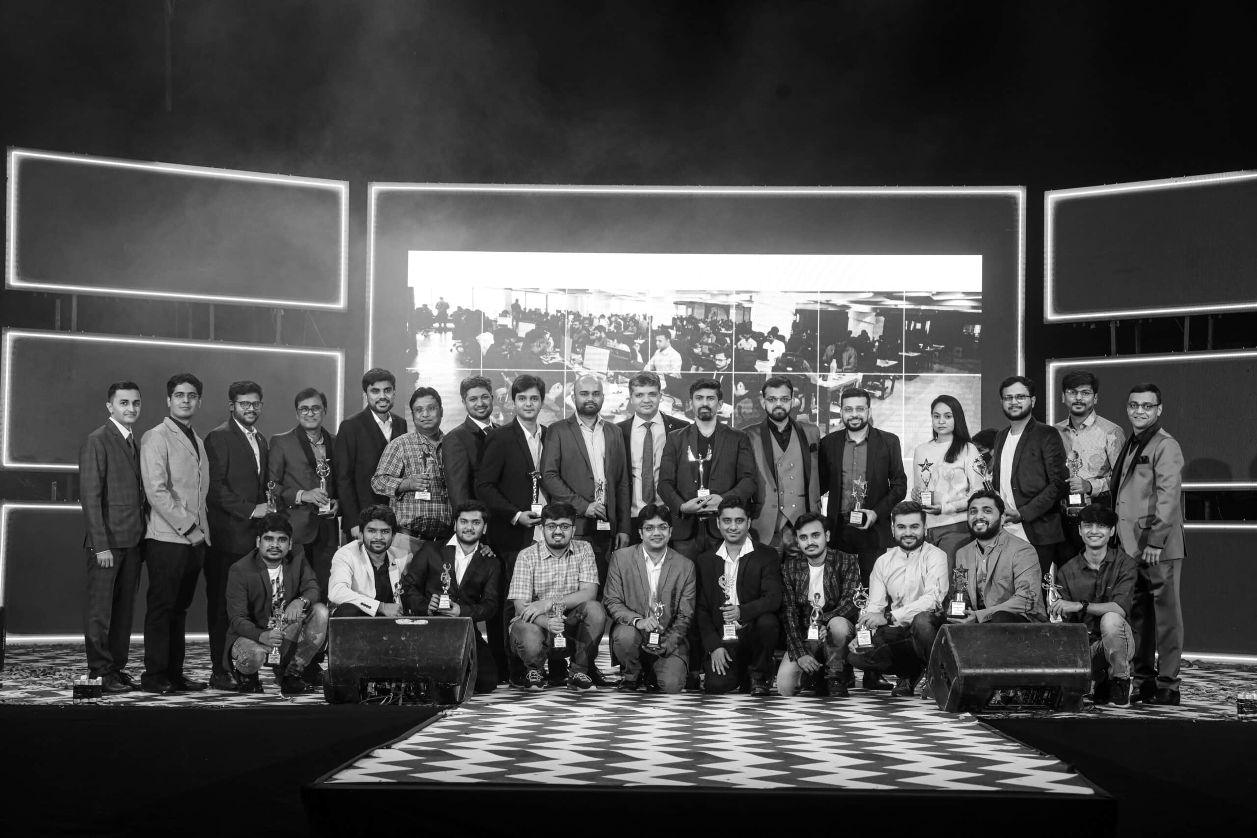 Jayesh Mori with Rapidops colleagues in a group photograph on a stage, several holding trophies