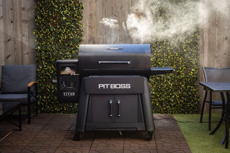 A Pit Boss Titan pellet grill producing smoke on a patio