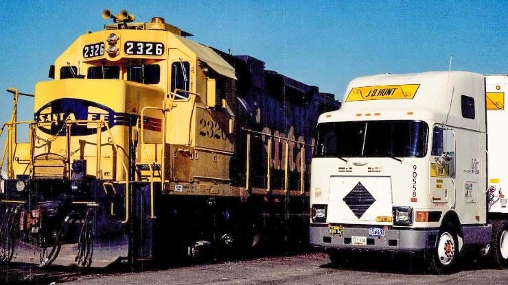 An archival Santa Fe locomotive beside a white J.B. Hunt tractor-trailer