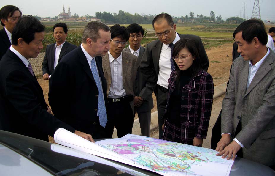 Jean-François Baril and a group examining a site plan outdoors in Vietnam in 2008