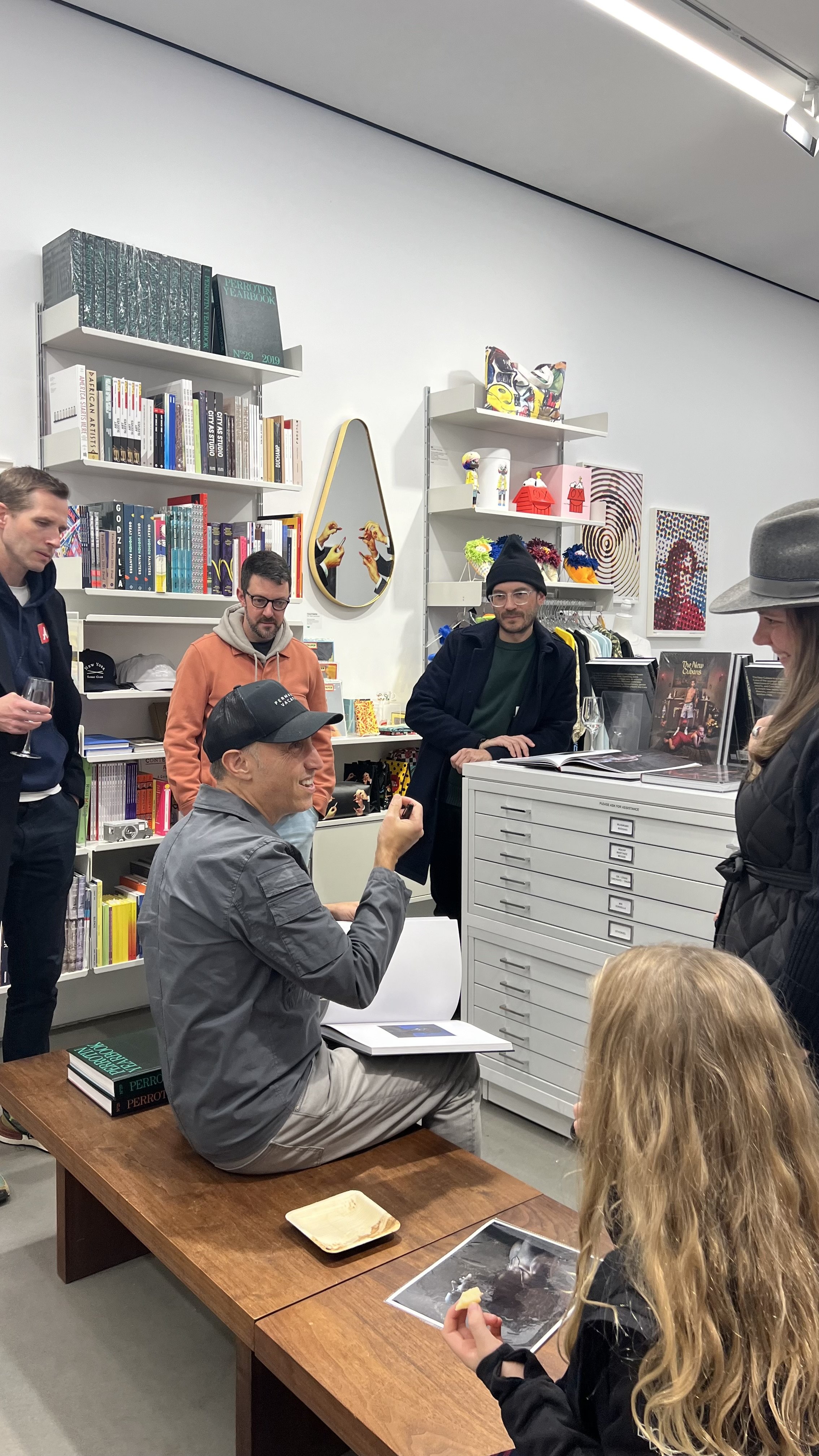 Jean-François Bouchard, seated with a book, talking with visitors at a launch event