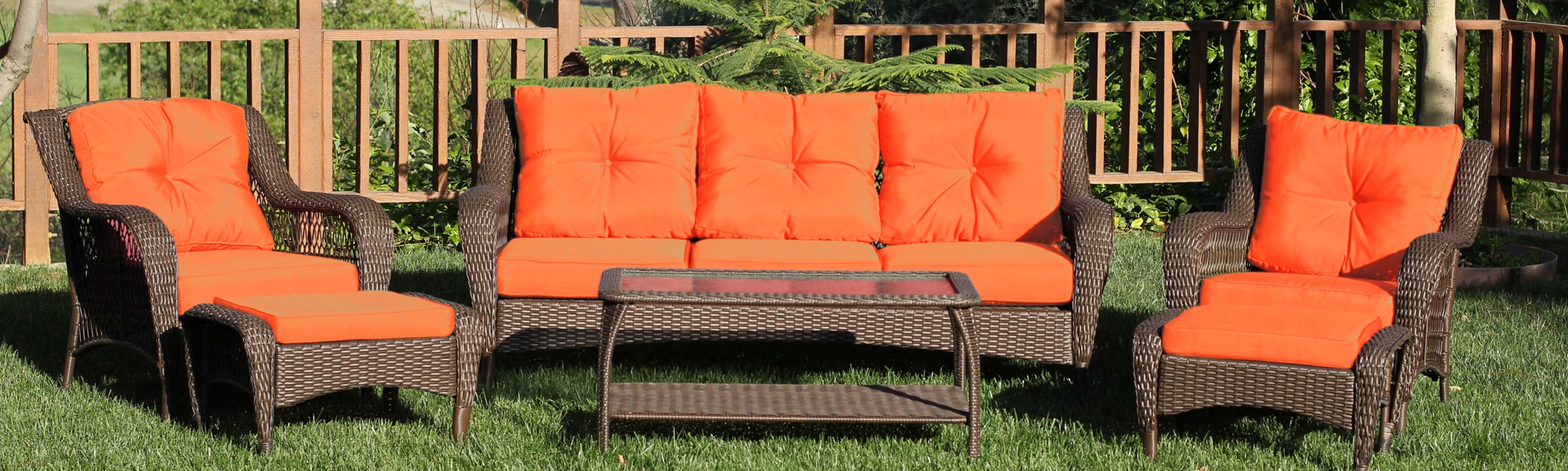 JECO brown wicker patio seating with bright orange cushions and a coffee table in a garden