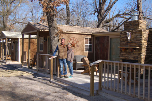 Jeff and Courtney Blankinship standing outside a wooden guest cabin at Broken Stone Ranch