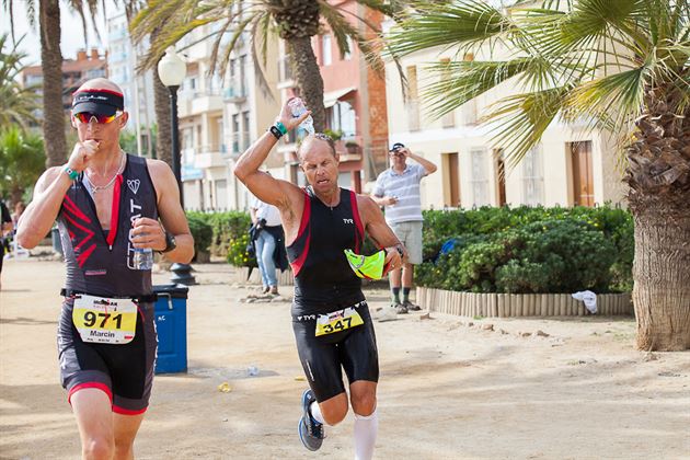 Jeff Crosby running during an endurance race, carrying water beneath palm trees