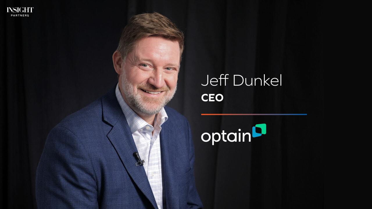 Jeff Dunkel smiling during an Insight Partners interview, wearing a blue jacket and a lapel microphone
