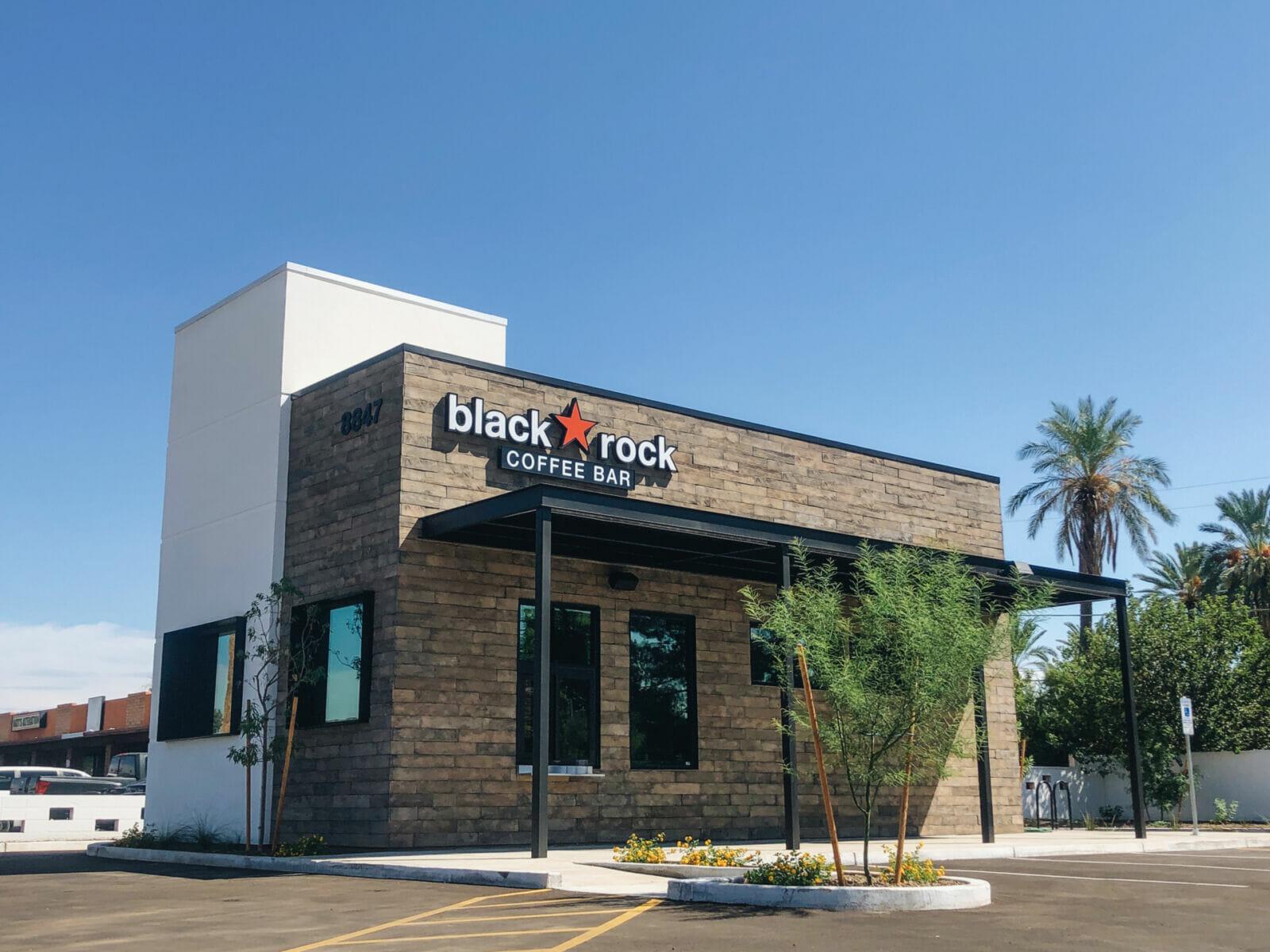 A Black Rock Coffee Bar building with a shaded entrance and palm trees