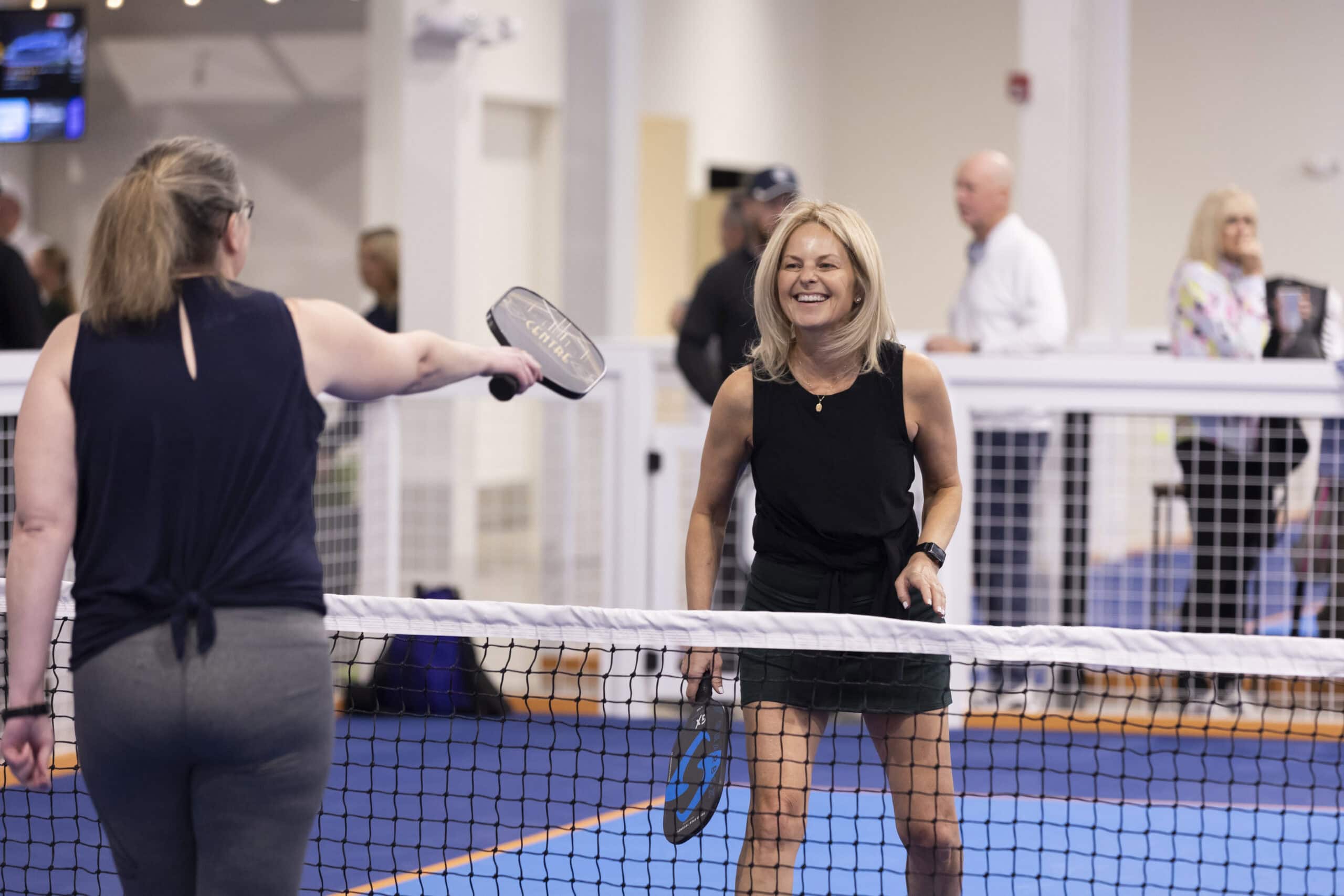 Players smiling across a net at Pickle Haüs
