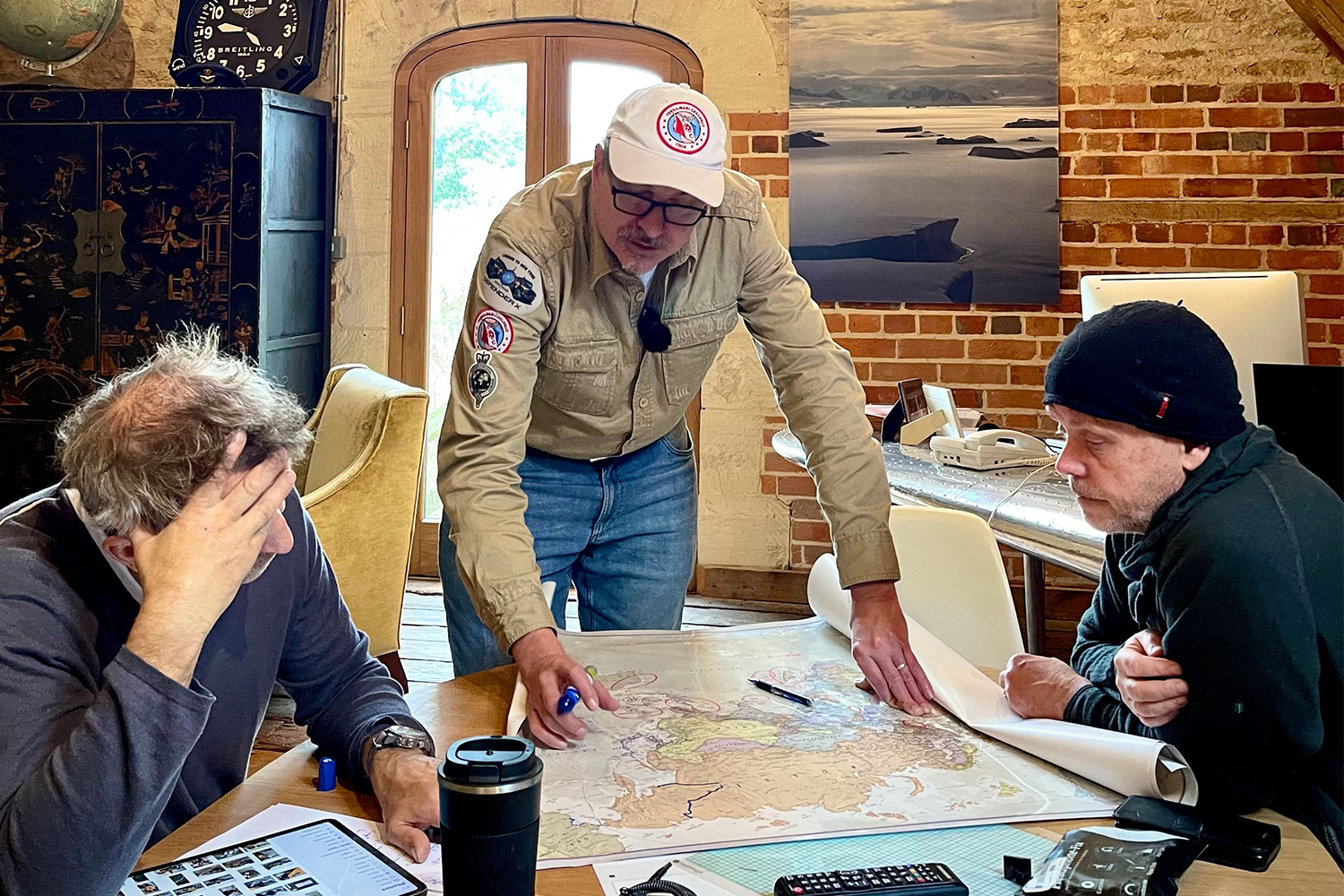 Steve Brooks at left, Jeff Willner in the center, and Mikael Strandberg at right studying maps around a table.