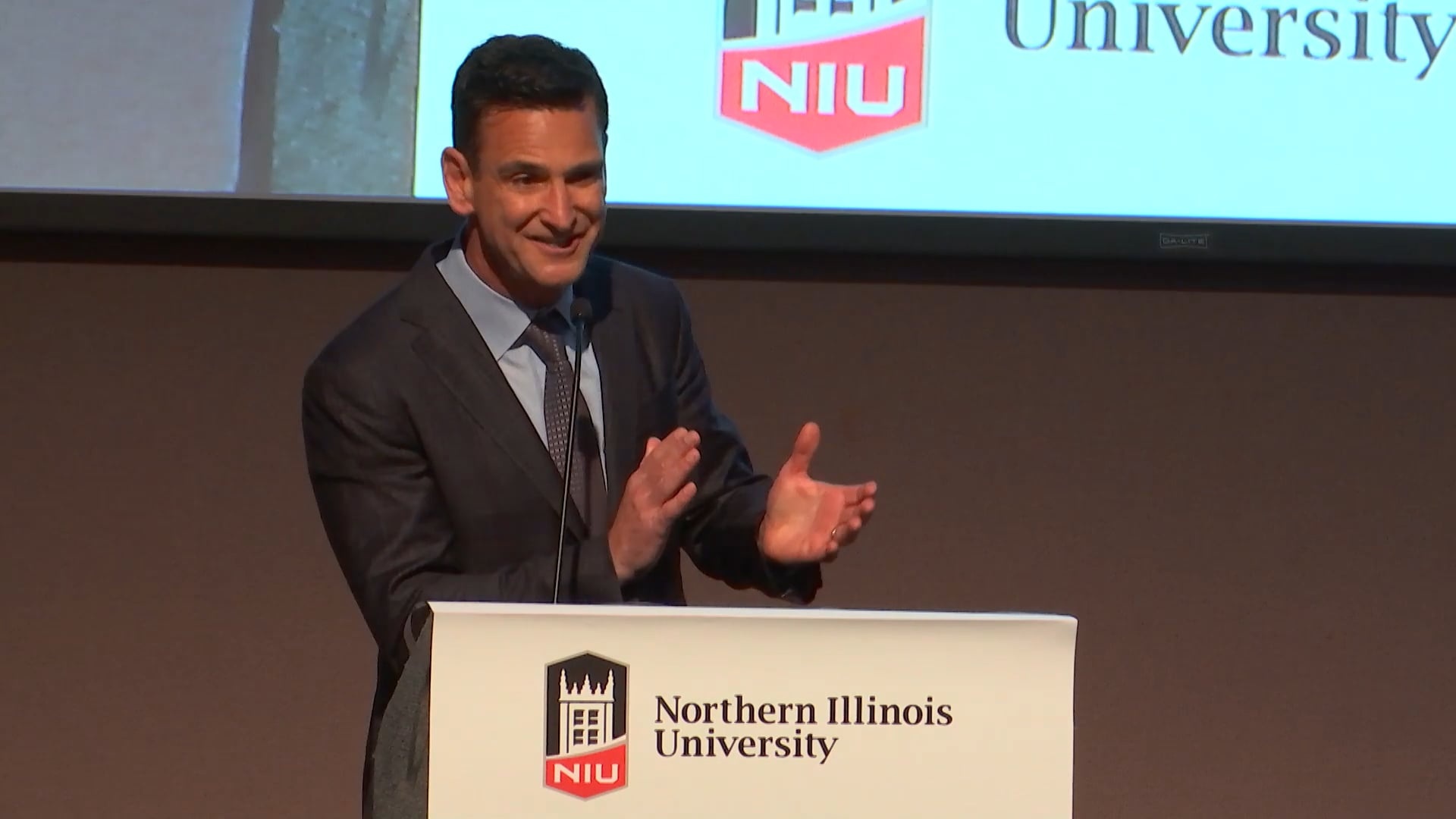Jeff Aronin speaking at a podium at Northern Illinois University’s 2019 alumni award event