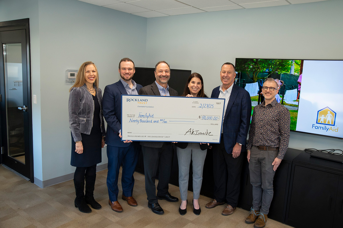 Six FamilyAid and Rockland Trust representatives hold a ceremonial $90,000 grant check; Jeffrey Tengel stands second from the right.