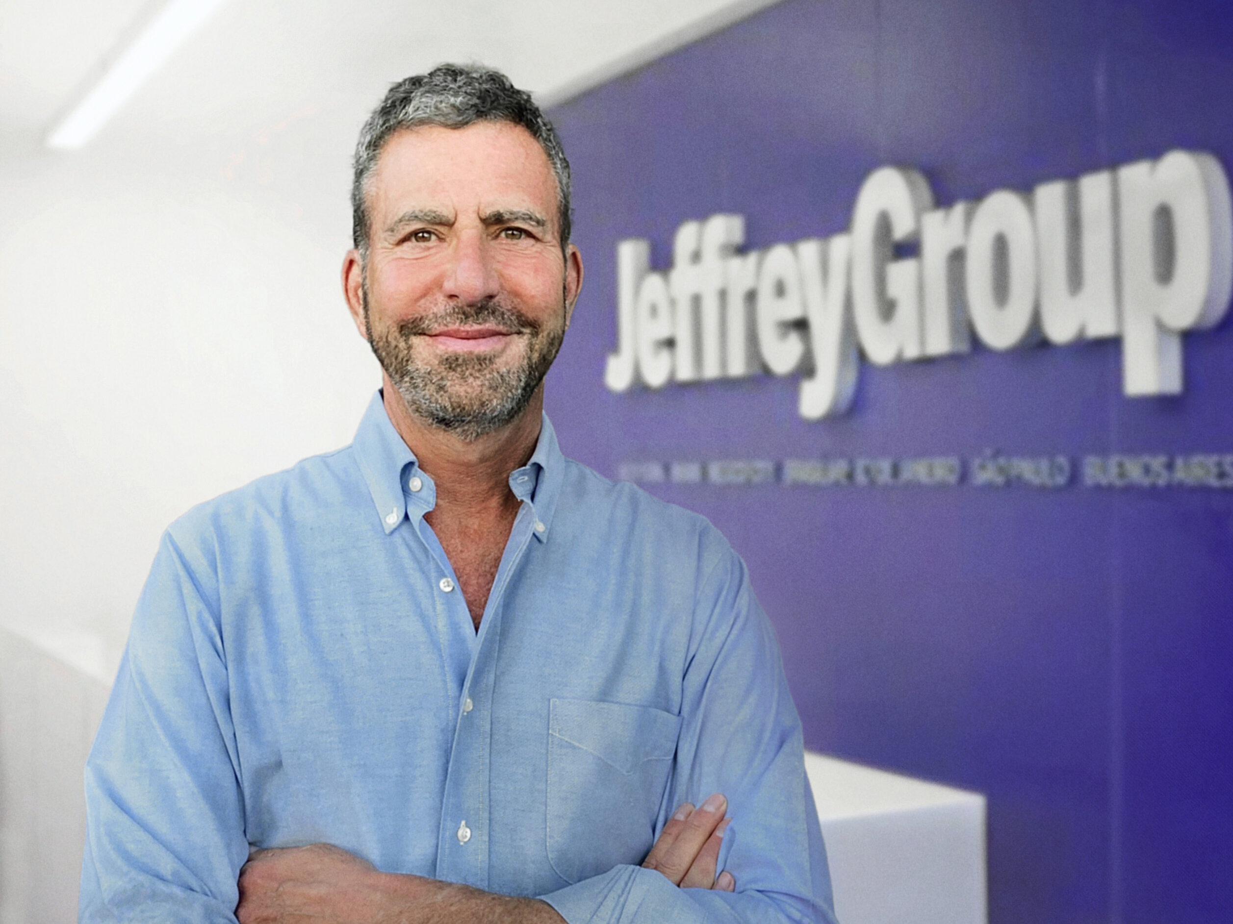 JeffreyGroup founder Jeffrey Sharlach standing beside company signage