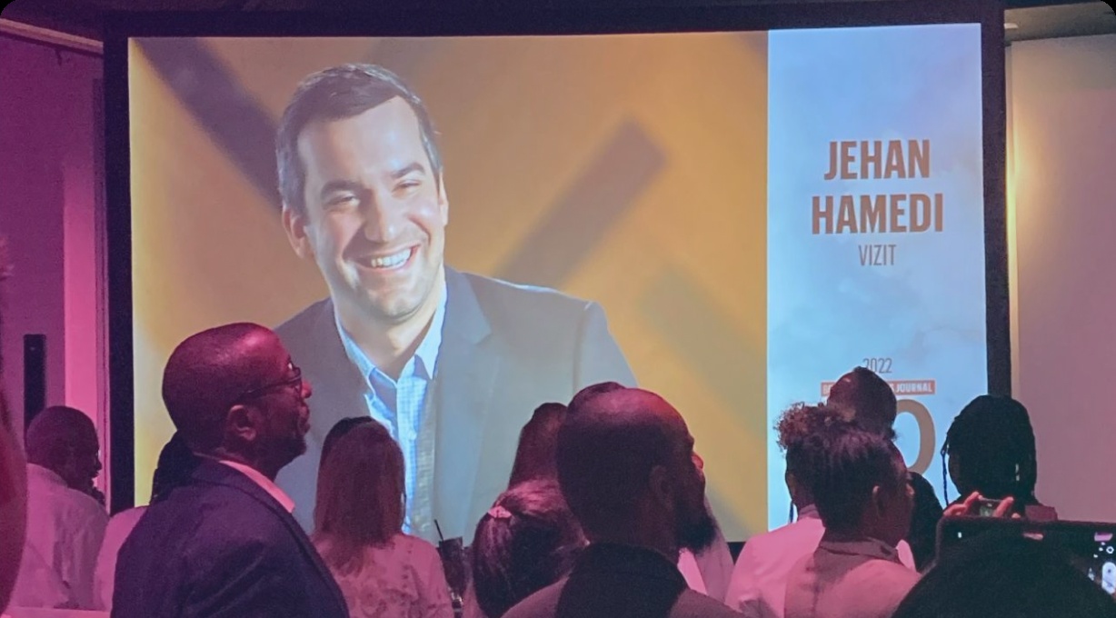 An event audience watches a screen honoring Jehan Hamedi in the 2022 Boston Business Journal 40 Under 40 class