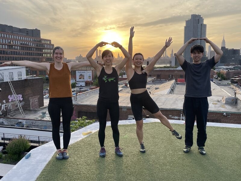 Four members of the Toko team on a rooftop at sunset, forming letters with their arms