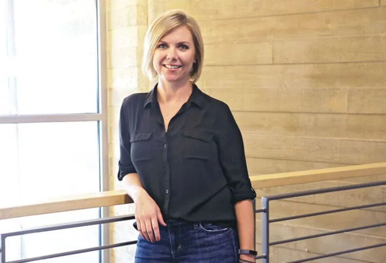 Jen Snell standing beside a railing in a bright modern building