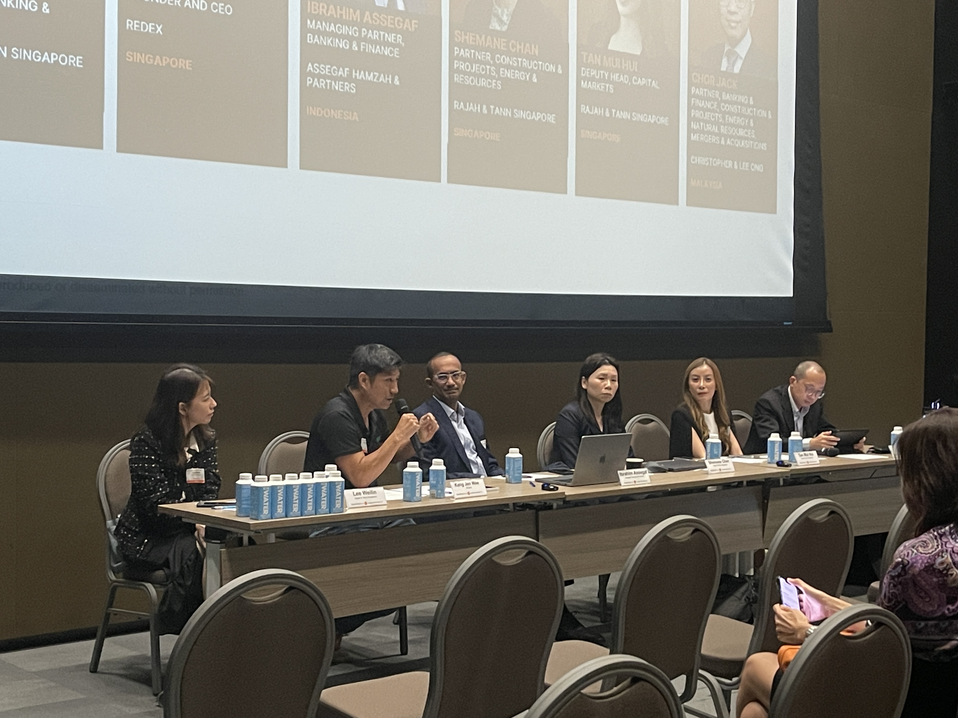 Jen Wee Kang, second from left, speaking into a microphone during a panel with legal professionals.